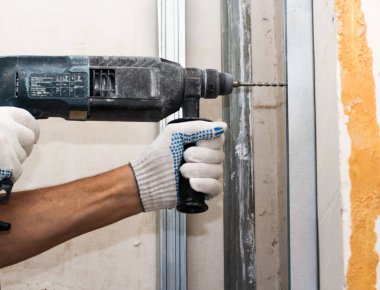 Duvara çekiçle vuruyor. Konut binalarının yeni apartmanlarında inşaat ve bitirme işleri.