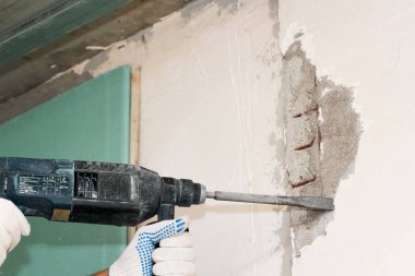 Düz bıçaklı bir deliciyle duvarları makasla kesiyor..