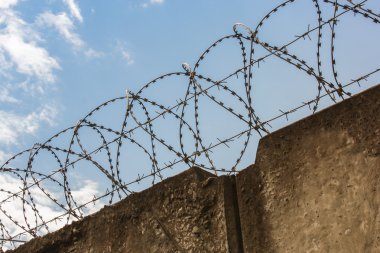Dikenli tel ile tepesinde bir beton duvar.