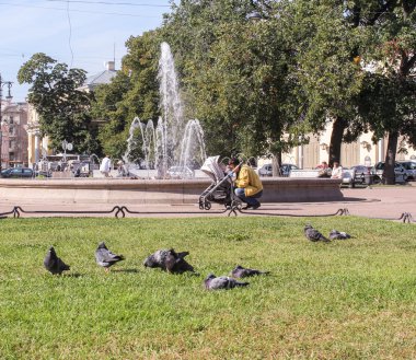 Genç adam bir çeşme ile bir parkta bir çocukla.