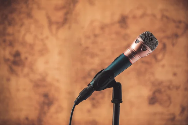 Black microphone with blurred old world map background — Stock Photo, Image