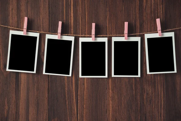 empty photo frames hanging with clothespins on wooden background