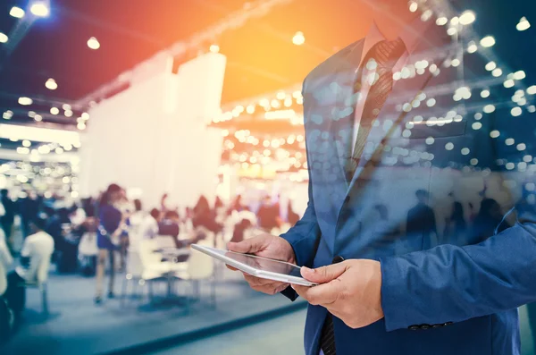 Empresário usando tablet com fundo de evento desfocado — Fotografia de Stock