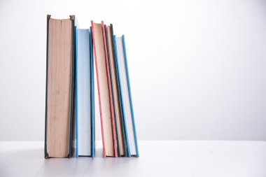 ahşap masa beyaz arka plan üzerinde kitap yığını