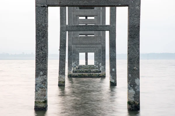 Symmetrie der Masten, lange Belichtung unter der Seebrücke — Stockfoto