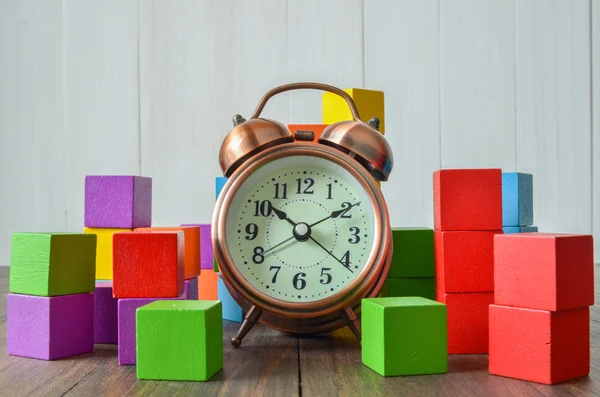 Montón colorido de bloques de construcción de cubo de madera y reloj despertador —  Fotos de Stock