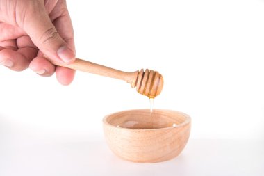 Beyaz backgr tatlım kase üzerinde ahşap bal ayı'yı tutan el