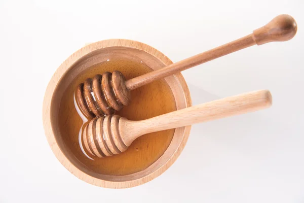 Two wooden honey dipper in honey bowl on white background — Stock Photo, Image