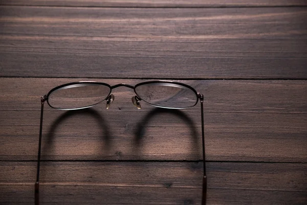 Hnědé brýle na dřevěný stůl — Stock fotografie