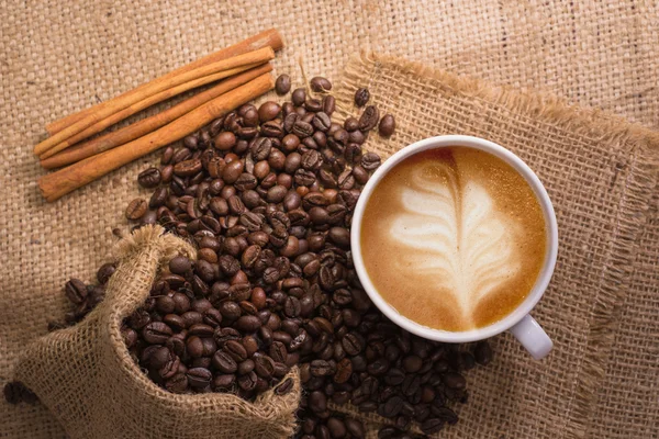 Witte koffiekopje en geroosterde koffiebonen rond — Stockfoto