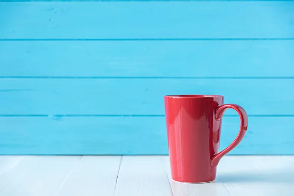 Röd kopp på blå trävägg bakgrund — Stockfoto