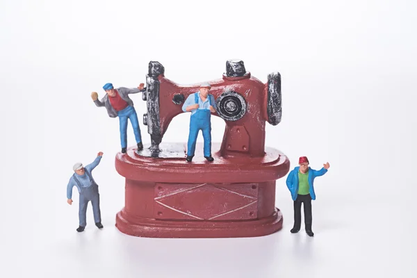 Miniaturmenschen und Nähmaschine auf weißem Hintergrund — Stockfoto
