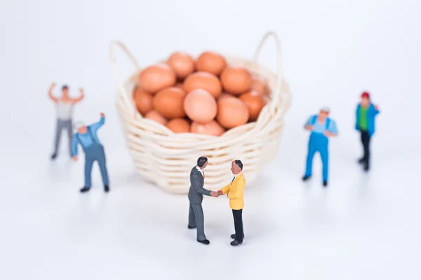 Miniature team make agreement with egg basket on white backgroun — Stock Photo, Image