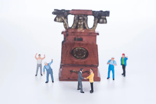 Persone in miniatura e telefono vintage su sfondo bianco — Foto Stock