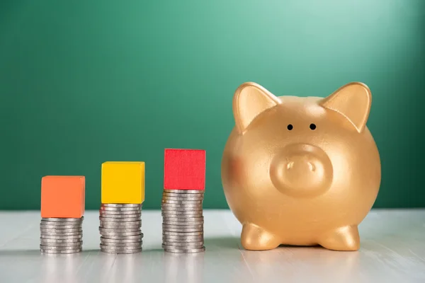 Cube wood block on growing coins stack and piggy bank — Stock Photo, Image