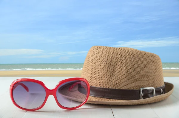 Красные солнцезащитные очки и шляпа моды на фоне моря и голубого неба — стоковое фото