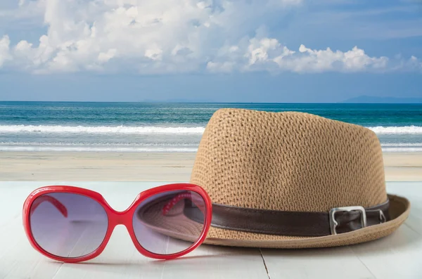 Rudé slunce brýle a módní klobouk na moře a modrá obloha pozadí — Stock fotografie