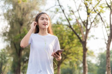 Genç kadınlar koşuyor ve yeniden başlamak için akıllı telefonundan müzik dinliyorlar.