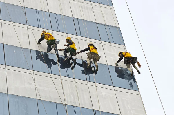 group of workers cleaning windows on high rise building