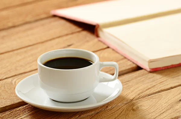 Een kopje koffie en een boek over houten tafel — Stockfoto