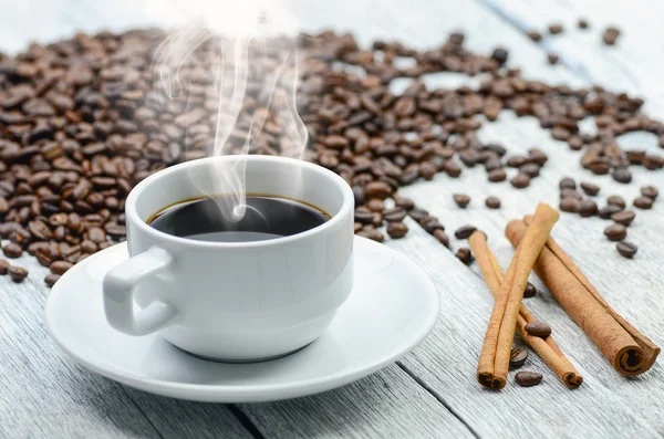 Coffee cup with smoke and coffee beans around — Stock Photo, Image