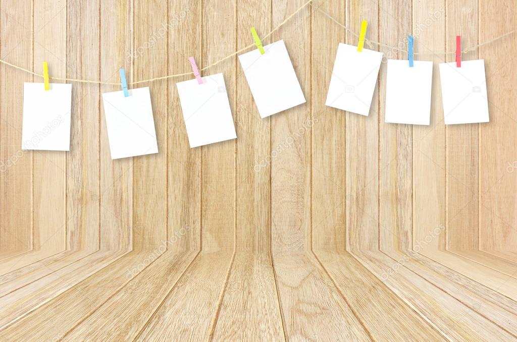 empty white photo frames hanging with clothespins on wooden back