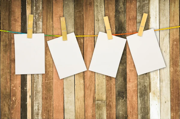 Empty white photo frames hanging with clothespins on wooden back — Stock Photo, Image