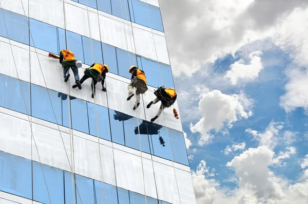 Grupo de trabajadores limpiando ventanas en un edificio de gran altura — Foto de Stock