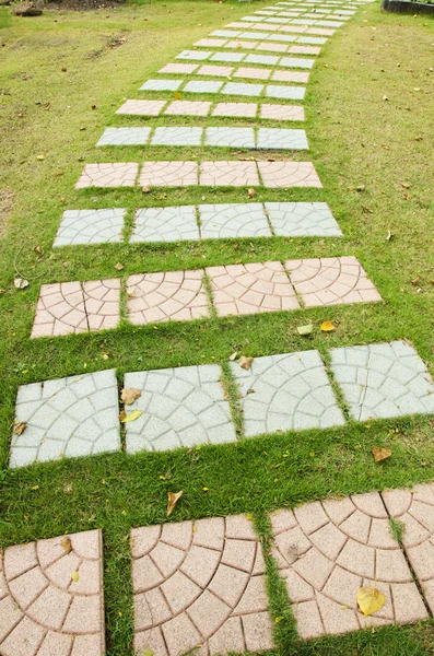 Colorful cement walkway on green grass — Stock Photo, Image