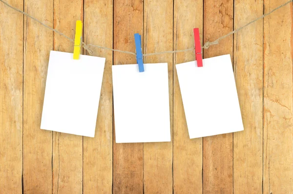 Three empty white photo frames hanging with clothespins on woode — Stock Photo, Image