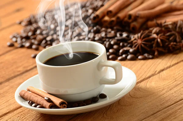 Koffiekopje met rook en koffie bonen rond — Stockfoto