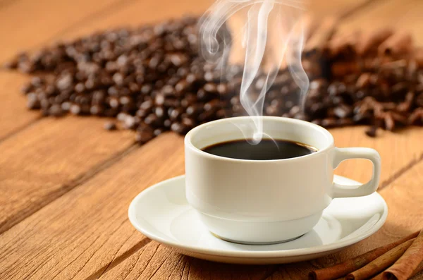 Tasse à café avec fumée et grains de café autour — Photo