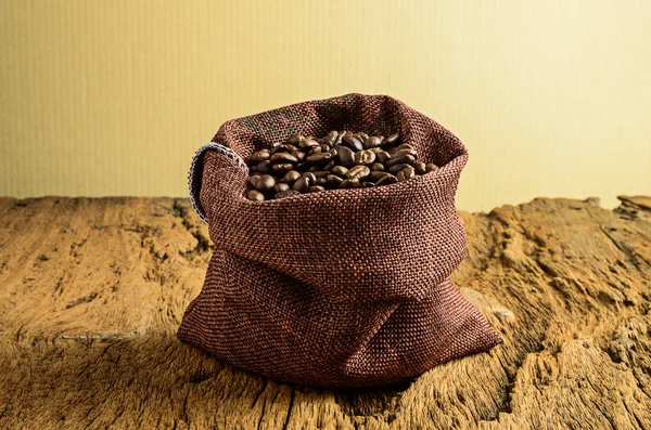 Roasted coffee beans in bag and coffee beans around — Stock Photo, Image