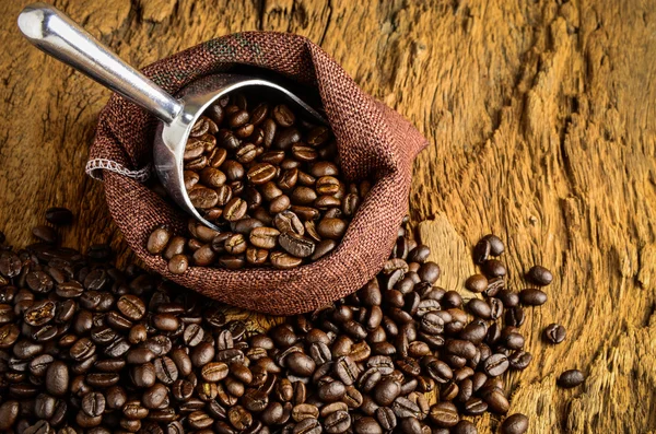 Granos de café tostados en bolsa y granos de café alrededor —  Fotos de Stock