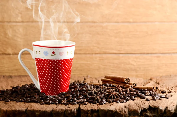 Taza de café en la mesa de madera y granos de café tostados alrededor — Foto de Stock