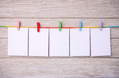 clothespins ile ahşap arkasında asılı boş beyaz fotoğraf çerçeveleri