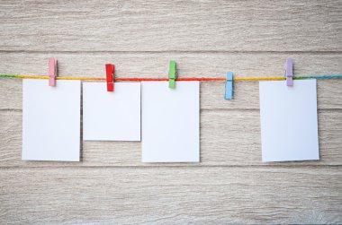 Clothespins ile ahşap arka plan asılı boş beyaz fotoğraf çerçeveleri