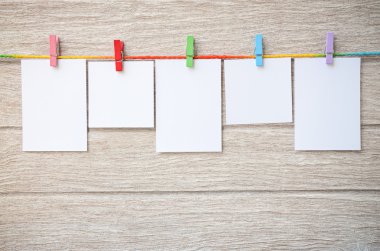 Clothespins ile ahşap arka plan asılı boş beyaz fotoğraf çerçeveleri