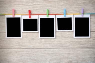 clothespins ile ahşap arkasında asılı boş siyah fotoğraf çerçeveleri