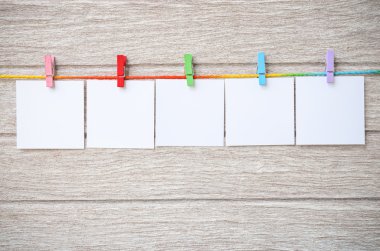 Clothespins ile ahşap arka plan asılı boş beyaz fotoğraf çerçeveleri