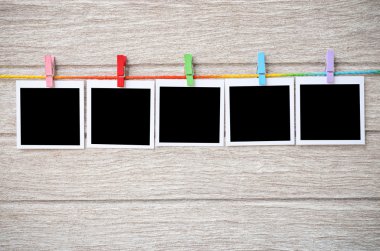 clothespins ile ahşap arkasında asılı boş siyah fotoğraf çerçeveleri