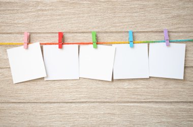 Clothespins ile ahşap arka plan asılı boş beyaz fotoğraf çerçeveleri