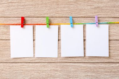 Clothespins ile ahşap arka plan asılı boş beyaz fotoğraf çerçeveleri