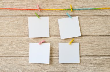 Clothespins ile ahşap arka plan asılı boş beyaz fotoğraf çerçeveleri