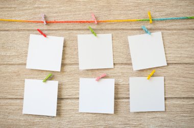 Clothespins ile ahşap arka plan asılı boş beyaz fotoğraf çerçeveleri