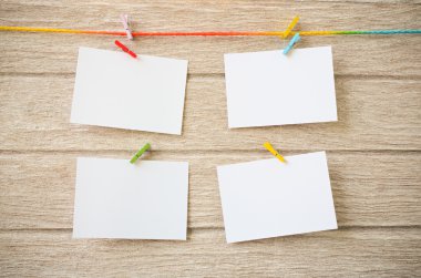 Clothespins ile ahşap arka plan asılı boş beyaz fotoğraf çerçeveleri