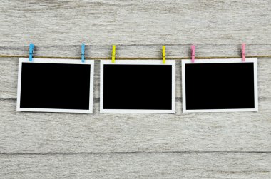 clothespins ile ahşap arkasında asılı boş siyah fotoğraf çerçeveleri