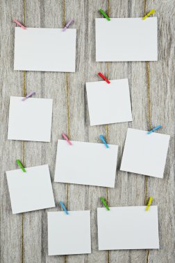 Clothespins ile ahşap arka plan asılı boş beyaz fotoğraf çerçeveleri