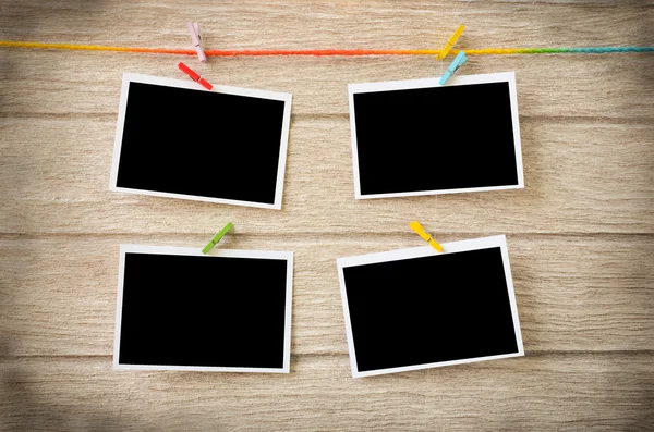 clothespins ile ahşap arkasında asılı boş siyah fotoğraf çerçeveleri