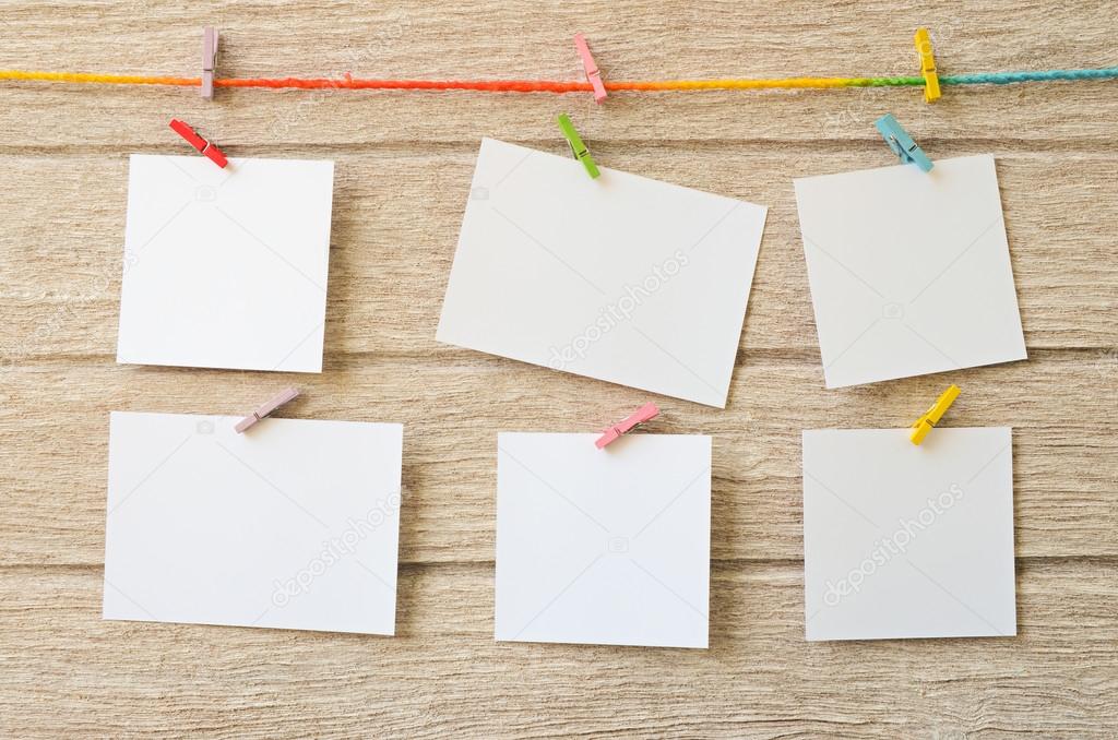 Empty white photo frames hanging with clothespins on wooden background